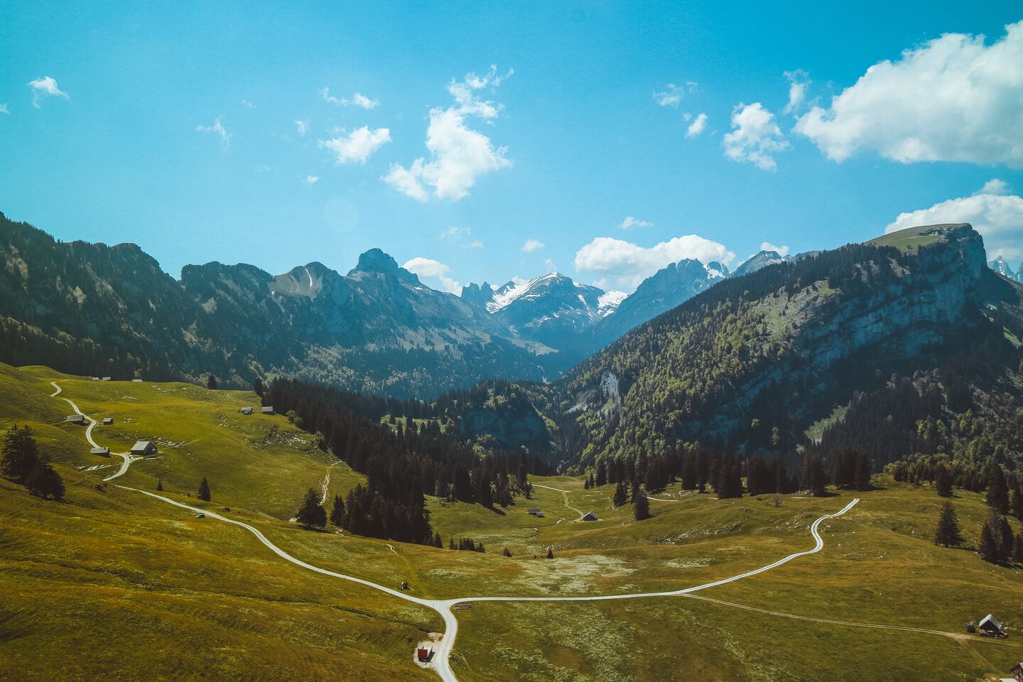 areal photograph of a mountain road splitting into two separate roads leading up and down hill